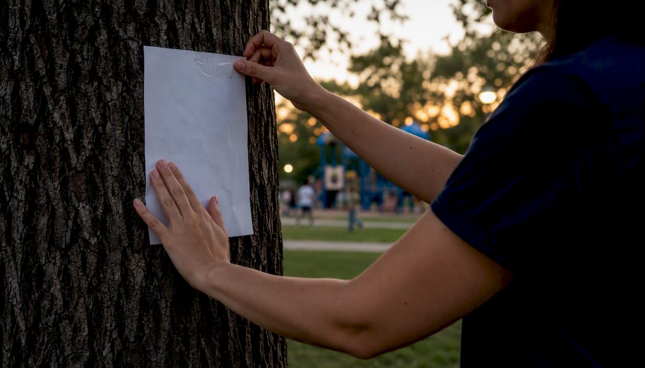Volunteer posting cold case awareness flyer outdoors