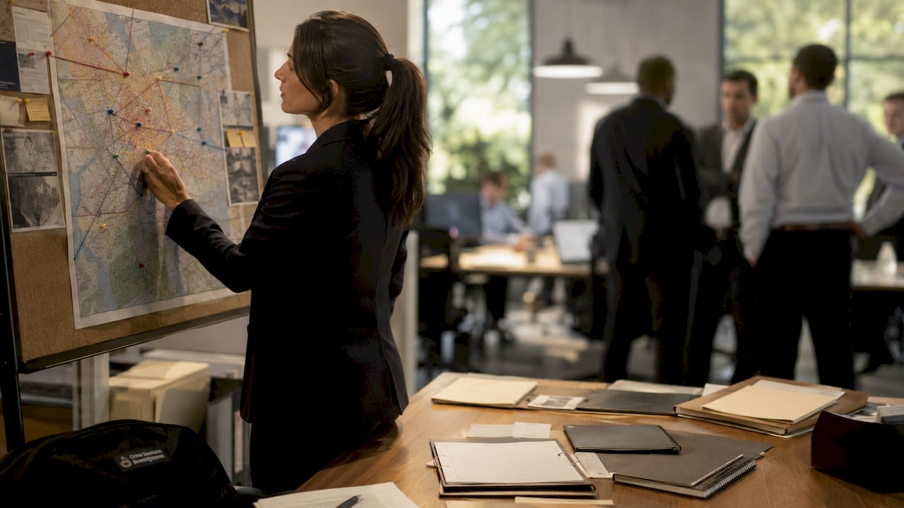 Hands placing pins on crime map for profiling